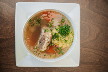 Diet soup with a small piece of pork and potatoes. Lean broth. Nutrition for gastritis. White bowl on a dark background