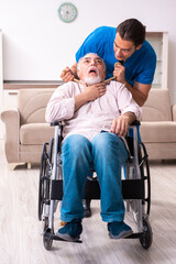 Fototapeta na wymiar Old man in wheel-chair and young bad caregiver indoors