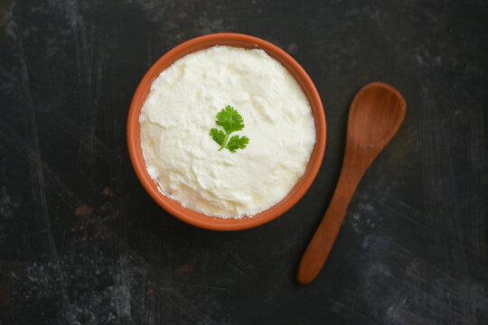 Bowl of homemade sour cream curd yogurt Dahi fresh herbs curry leaf Kerala, India. Dairy product obtained by coagulating milk a process curdling. probiotic food. tasty curd rice curry spices