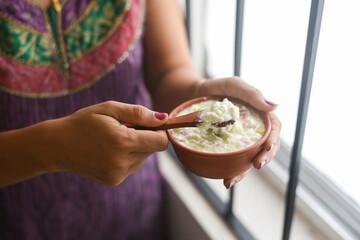 Bowl of homemade sour cream curd yogurt Dahi fresh herbs curry leaf Kerala, India. woman hand take dairy product obtained coagulating milk process curdling. probiotic food tasty curd rice curry spices