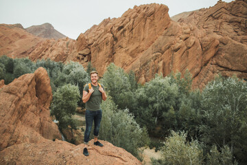 Portrait of happy smiling european backpacker man on background of Todra gorge canyon in Morocco....