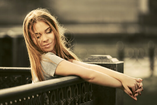 Happy young fashion woman in gray t-shirt leaning on railing