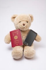 パスポートとスマートフォンを持ったクマのぬいぐるみ