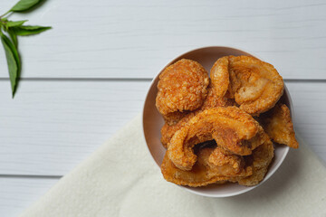 Pork rind in white bowl on white wooden floor