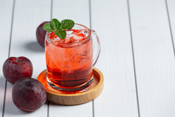 a glass of plum put on white wooden floor