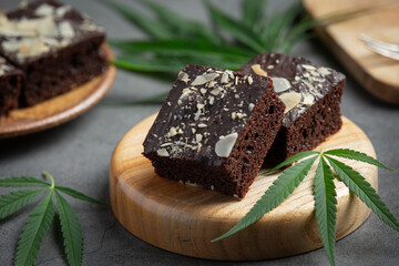 cannabis brownies and cannabis leaves put on wooden cutting board