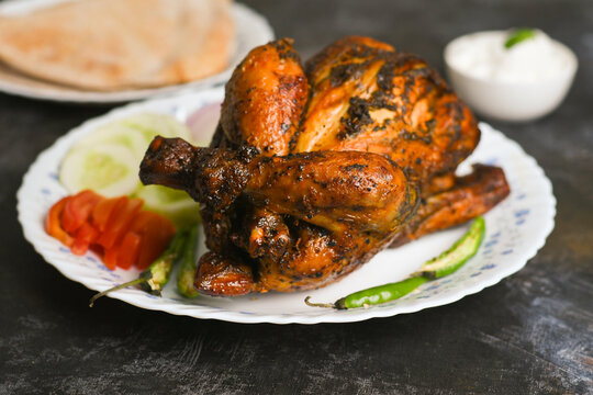 A plate of full thandoori chicken , Arabian spicy food tandoori whole chicken Bengaluru, India . Platter served with salads. Al Faham Charcoal Grilled Chicken . 