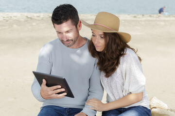 Naklejka premium young couple using a digital tablet at seaside town