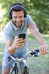 young sportsman riding bicycle holding smartphone