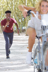 Obraz premium happy couple running behind woman riding bicycle