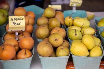 A slight elevated view of three rows of cartons of an assortment of pears on a farm stand table
