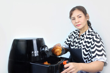 an asian lady woman model is cooking the croissant for the breakfast by using oil - free air fryer...