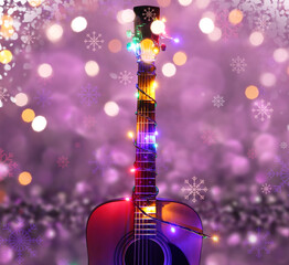 Acoustic guitar with Christmas lights against color background