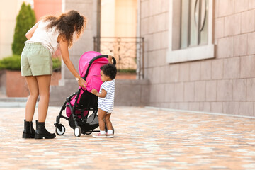 African-American woman with her cute baby and stroller outdoors