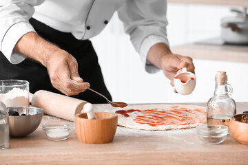 Obraz na płótnie Canvas Mature male chef cooking tasty pizza in kitchen, closeup