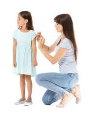 Mother giving her diabetic daughter insulin injection on white background