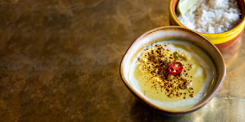 Yellow curry with cauliflower and chickpea and rice on metal tabletop background. Indian food. Vegetarian curry with copy space for text or design