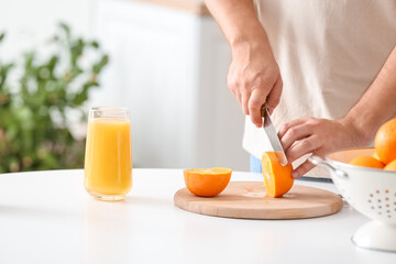 Man cutting orange in kitchen, closeup