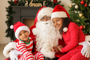 Fototapeta na wymiar African-American Santa Claus with cute children at home on Christmas eve