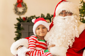 Fototapeta na wymiar African-American Santa Claus with cute boy at home on Christmas eve