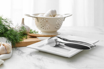 Garlic press with plate on light background