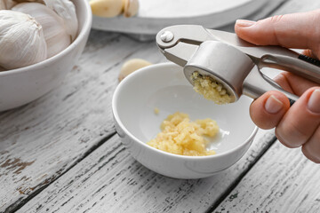 Woman squeezing fresh garlic into bowl