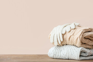 Stylish Christmas clothes on table against color background