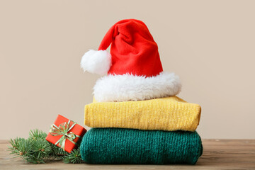 Obraz na płótnie Canvas Stylish Christmas clothes with Santa Claus hat on table against color background