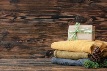 Stylish Christmas clothes with gift on table