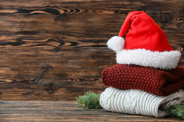 Obraz na płótnie Canvas Stylish Christmas clothes with Santa Claus hat on table