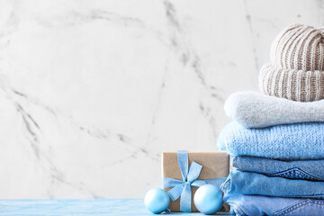 Stylish Christmas clothes with gift on table