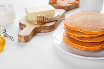Tasty pumpkin pancakes with ingredients on table