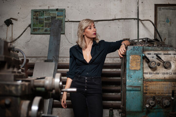 Portrait of a beautiful young blonde woman with blue eyes with old machinery 
