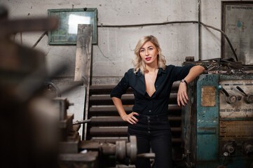 Fototapeta na wymiar Portrait of a beautiful young blonde woman with blue eyes with old machinery 