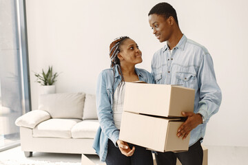 Young couple moving in to new home together. African american couple with cardboard boxes.