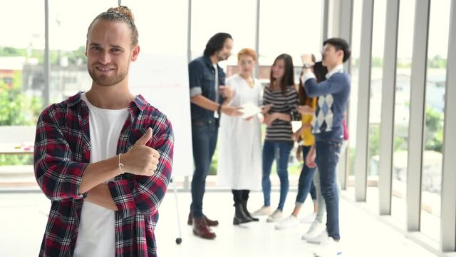 Portrait of young successful businessman and his team at the background.