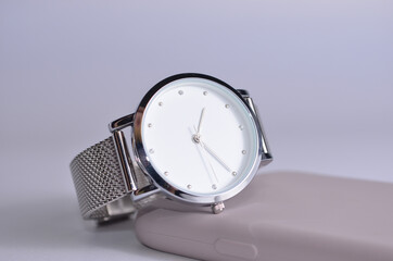 Women's watch with a silver strap and a telephone on the table.