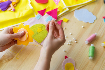 female hands making sun out felt. Accessories for needlework on wooden table. © skif