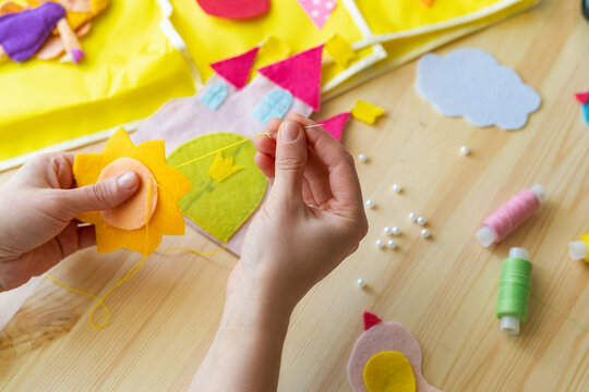 female hands making sun out felt. Accessories for needlework on wooden table.