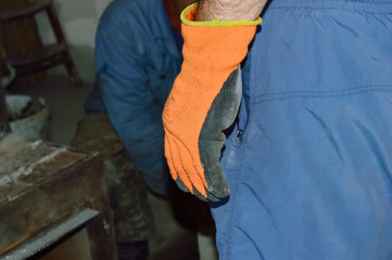 close-up - orange glove of a man against the background of a working moment and a working companion