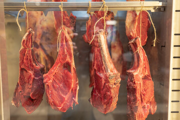 fresh raw meat on the bone hanging from a rope in a shop window