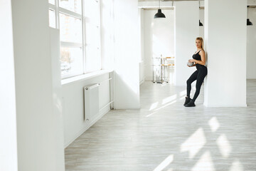 blonde warms up in the gym. A young sportswoman in a black suit gives a stretching while standing in the trunk hall. gymnastics
