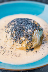Steamed sweet dumpling bun topped with poppy seeds and vanilla sauce.