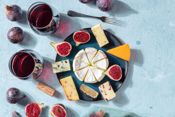 Cheese platter with wine and fruit, overhead photo with a place for text, a flatlay on a blue background