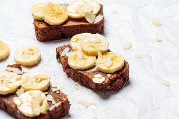 Pieces of banana bread with syrup and nuts on white background, copy space. Vegan dessert concept.