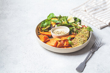 Falafel salad bowl. Vegan lunch plate - baked chickpea cutlets with baked sweet potatoes and vegetable salad in a white plate.