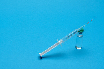medical vaccine ampoule and syringe over blue background