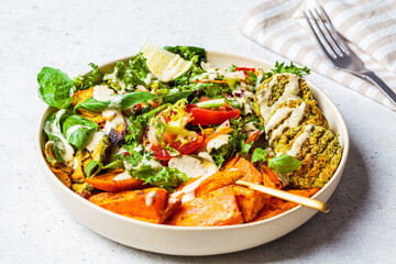 Falafel salad bowl. Vegan lunch plate - baked chickpea cutlets with baked sweet potatoes and vegetable salad in a white plate.