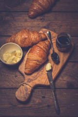 French croissant. Freshly baked croissants with jam on wooden background. Tasty croissants with copy space