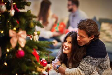 Adult couples having fun over Christmas tree